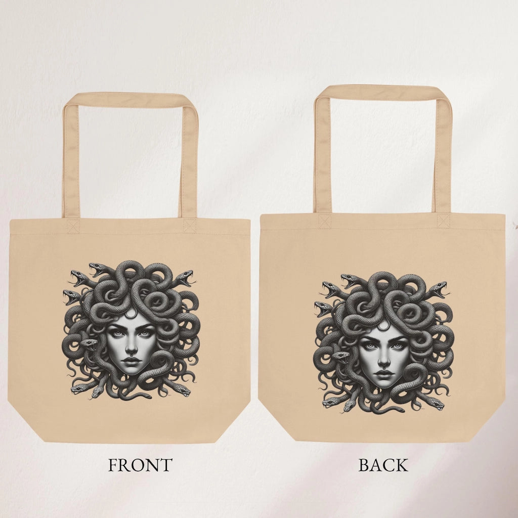 Beige tote bag with detailed Medusa artwork, featuring snake hair, held indoors by a hand